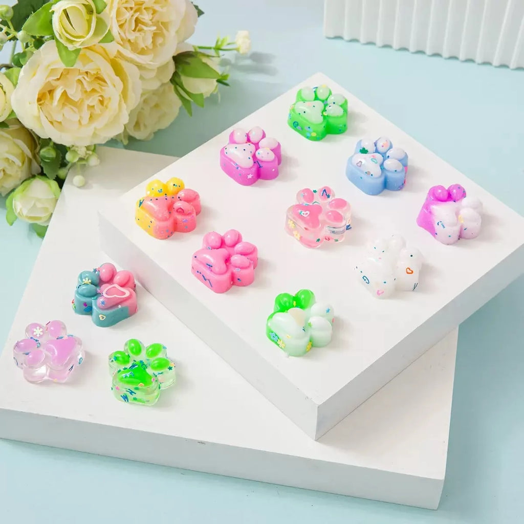 Squishy-kissantassuja pastellisävyissä valkoisella korokkeella kukkien vieressä