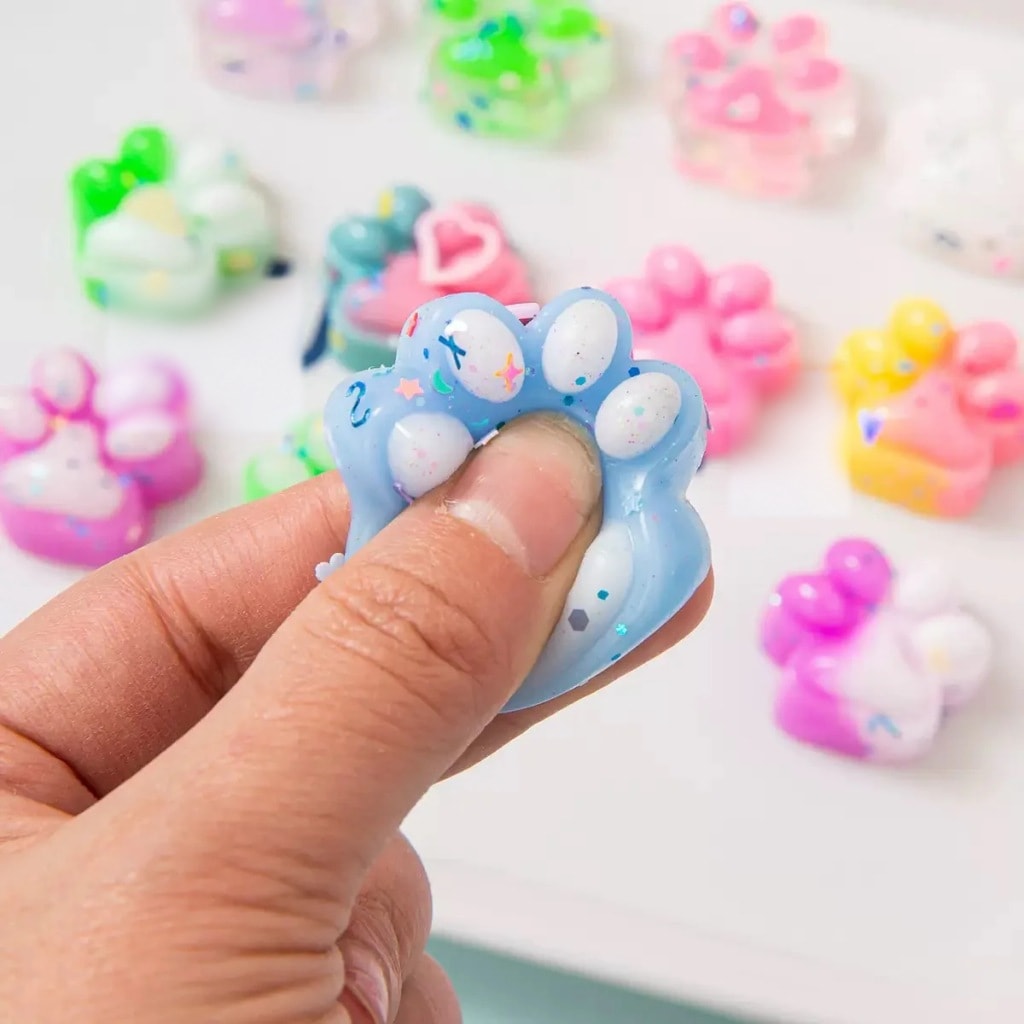 Käsi puristaa sinistä squishy-kissantassua