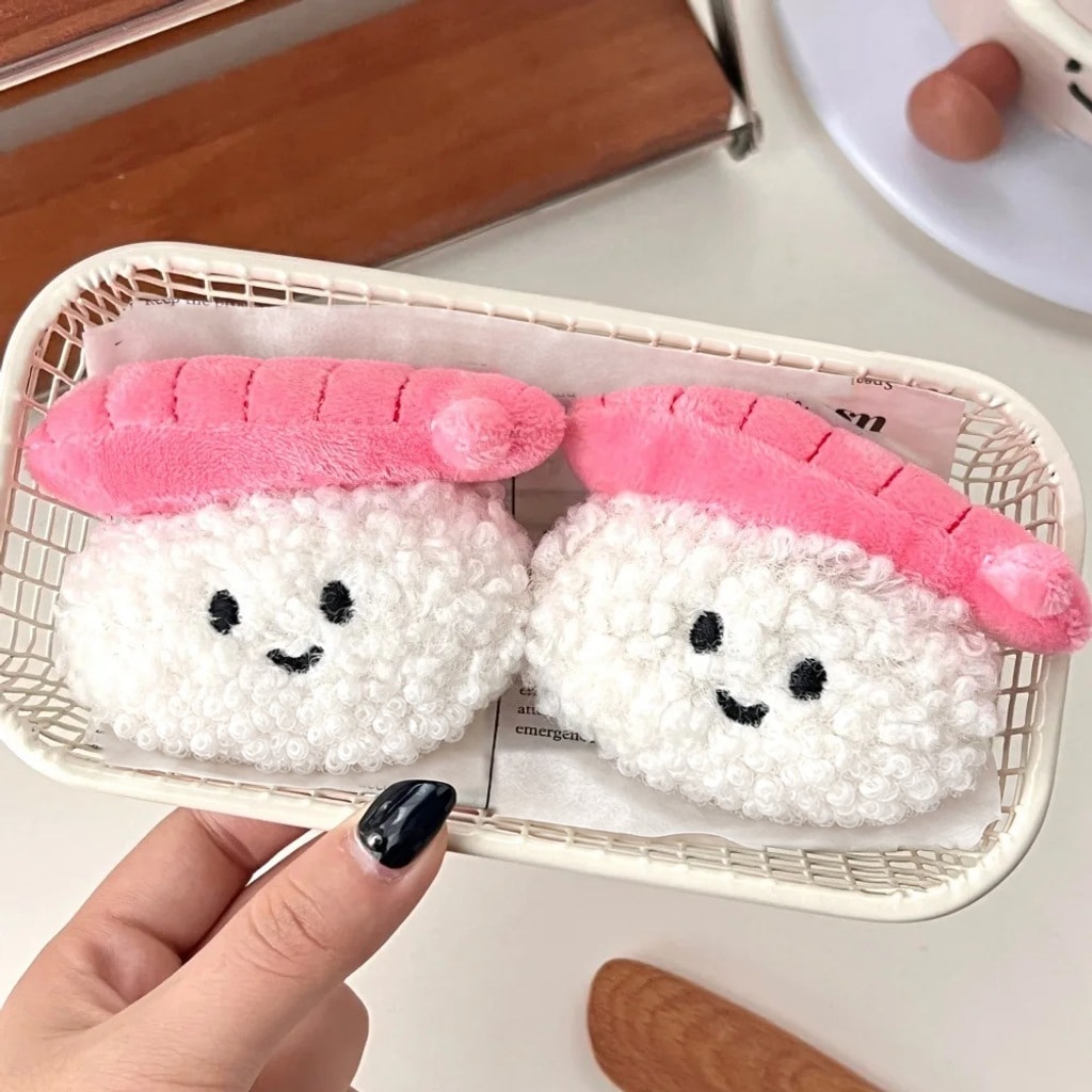 Kaksi hymyilevää pehmoista sushi-avaimenperää korissa
